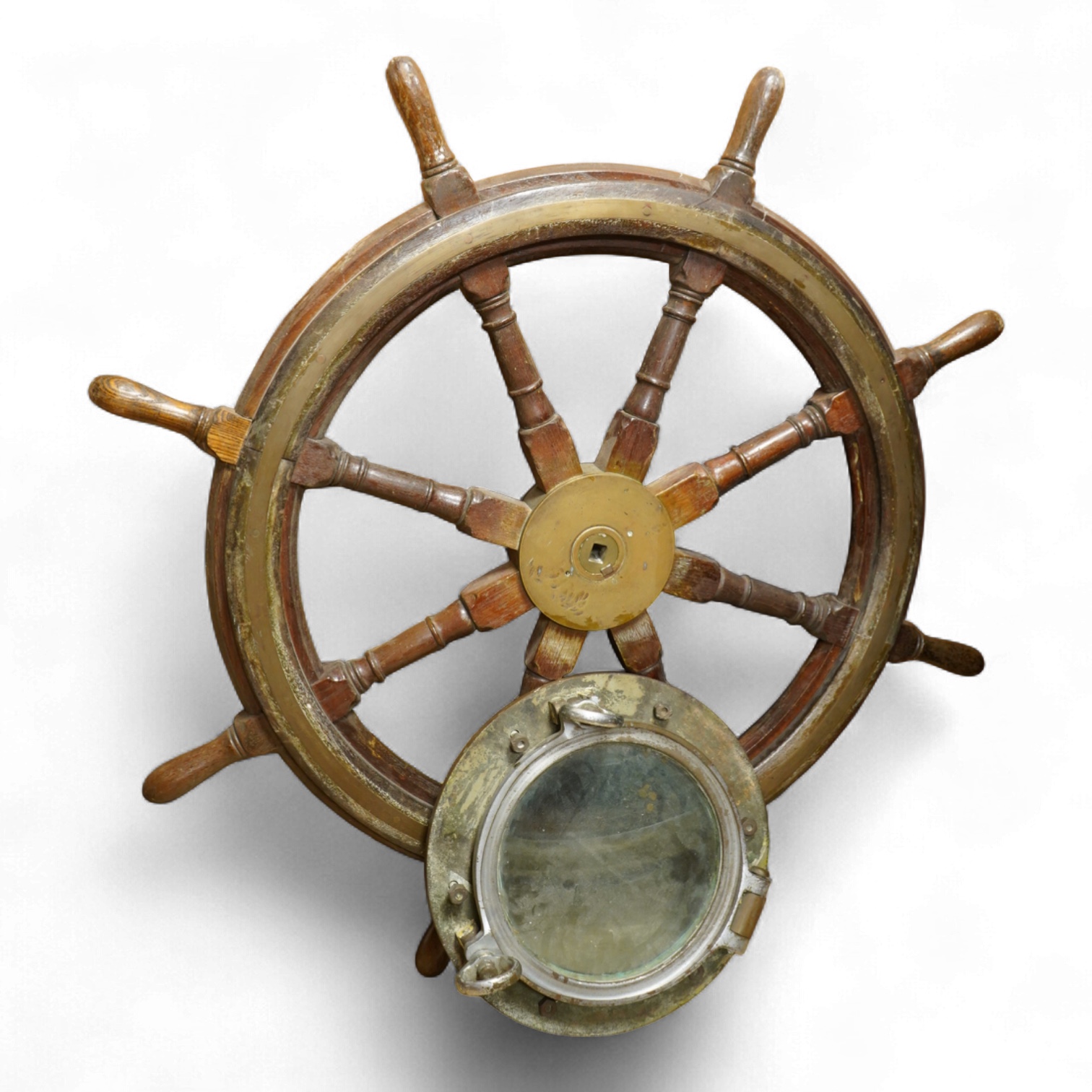 A mahogany ships wheel, diameter 80cm, and a brass and chrome porthole, diameter 39cm, by repute off HMS Uganda
